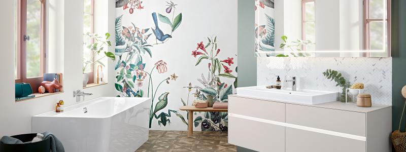 En ljus, ombonad miljö från Villeroy & Boch. Generösa Collaro handfat i TitanCeram finns i många former och storlekar. Badkaret i samma kollektion är i akryl 
och kan fås i andra färger. Skarpa linjer i kritvitt mot den blommiga tapeten ger en fräsch känsla. Foto Villeroy & Boch