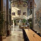 Det stora entréplanet har grafiska rutgolv i svart och vitt, betong, stålkonstruktioner och grå väggar kontrasteras av trämöbler, läder och textilier i chokladbrunt och varma toner.