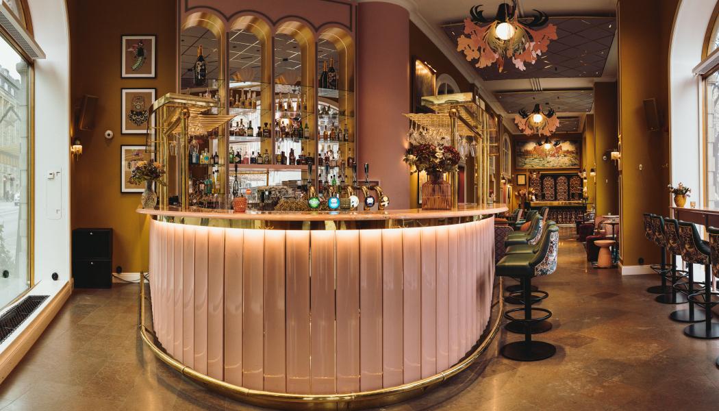 På bilden syns den nya cocktailbaren där väggarna är målade i en vacker senapsgul färg som går i kontrast med de rosa och gröna,
guldiga tonerna som binder ihop rummets detaljrikedom. Foto: Christian Fang