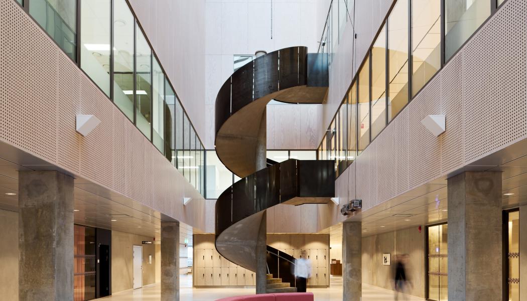 Atriet sett från plan 2. Skulptural trappa med räcke av stålplåt som förbinder labbet med mötesrummen och pausrummen. 
Bild: Mads Frederik arkitekturfotografi