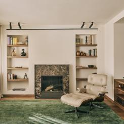 Den långa soffan mot en eldstaden inramas av exklusiv Emperador Dark-marmor och två nischer med hyllor på båda sidor. Foto: Claudia Mauriño
