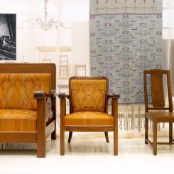 Möbler i jugendstil från verkstädernas tidiga år, kring 1910. Soffan och fåtöljen ritades av NK:s chefsarkitekt David Blomberg och stolen av Carl Westman, för Nyköpings tingshus. Textilier har alltid funnits med i NK:s utställningar och i de uppbyggda miljöerna på varuhuset. Gardinlängden är från Thyra Grafströms textilateljé, för en NK-miljö på Baltiska utställningen i Malmö 1914. Foto: Björn Dahlgren/Sörmlands museum